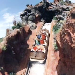 Riders descending a steep water flume drop surrounded by rocky canyon walls at a theme park attraction