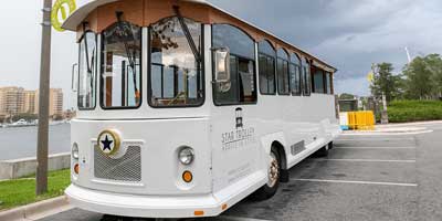 Star Trolley parked near a waterfront, a white vintage-style trolley bus used for tours