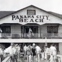Historic black-and-white photo of a beachside building with Panama City Beach sign, people gathered outside in swimwear