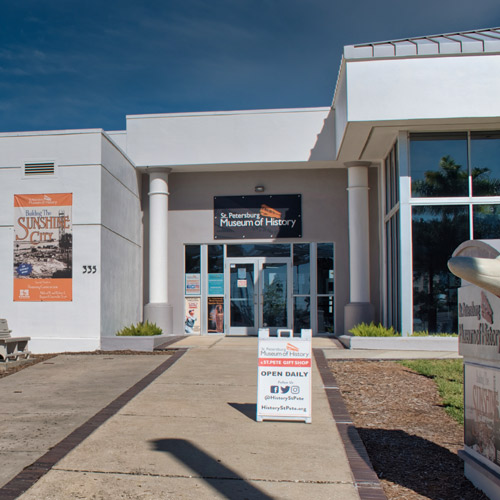 Exterior of the St. Petersburg Museum of History with an open daily sign and entrance doors visible