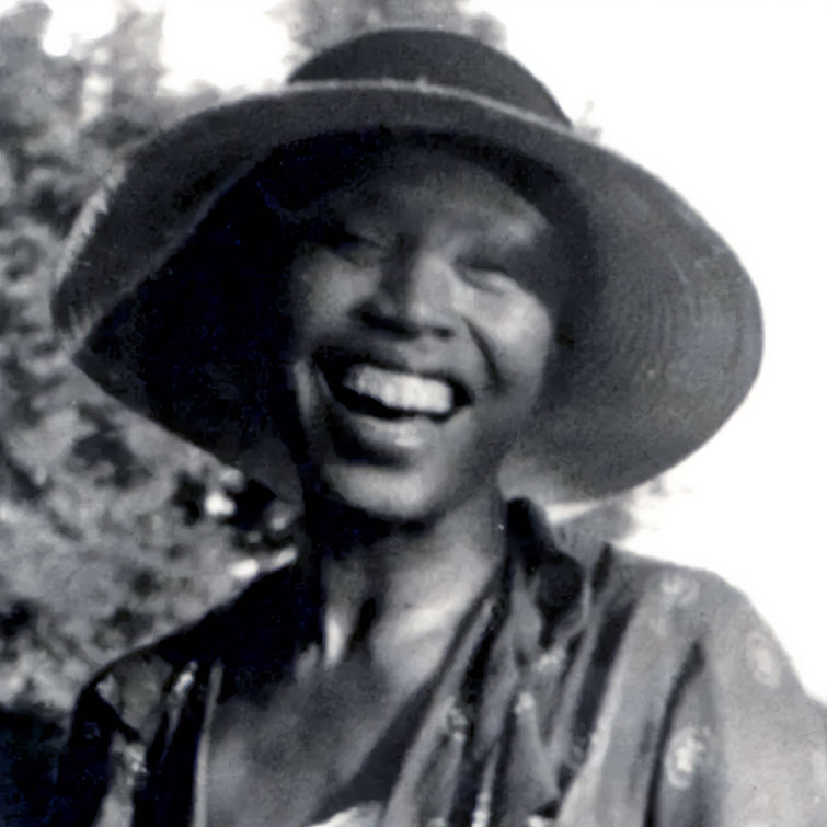 Photo of a black woman smiling with a wide brimmed hat