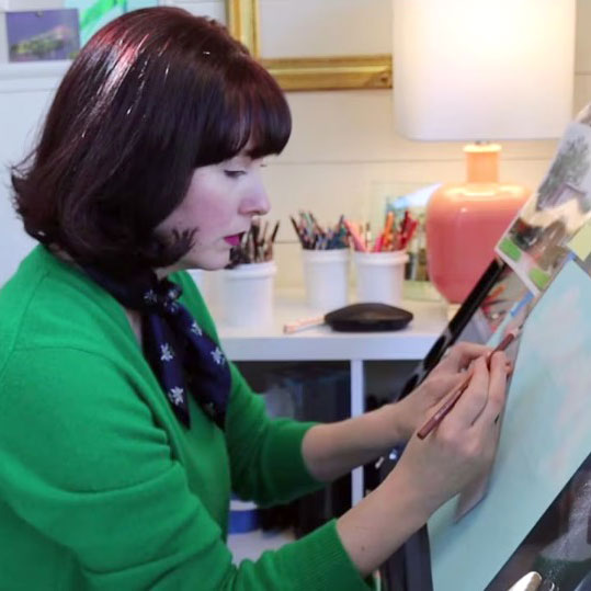 Young woman with dark colored hair wearing a green sweater while sketching on an easel