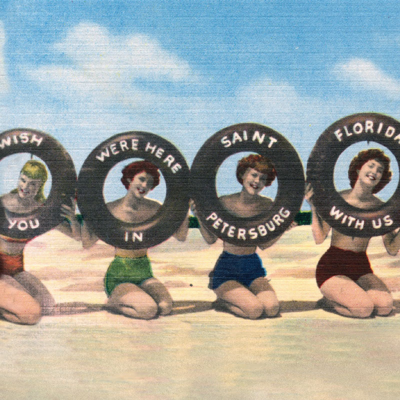 Four young women on a beach in swimsuits holding up inner tubes with the words 