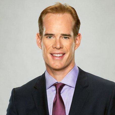 Photo of sports caster, Joe Buck, a lean man with light brown hair wearing a dark suit with a lavender shirt
