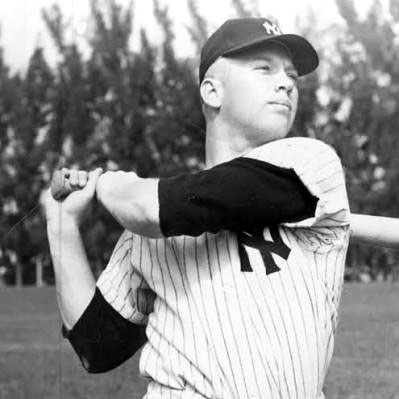 Baseball player, Mickey Mantle, swings for a pitch while wearing a striped NY Yankees uniform