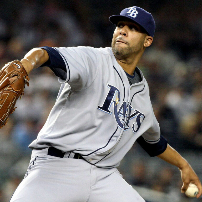 Baseball player in Rays uniform has his arm back, preparing to throw a baseball