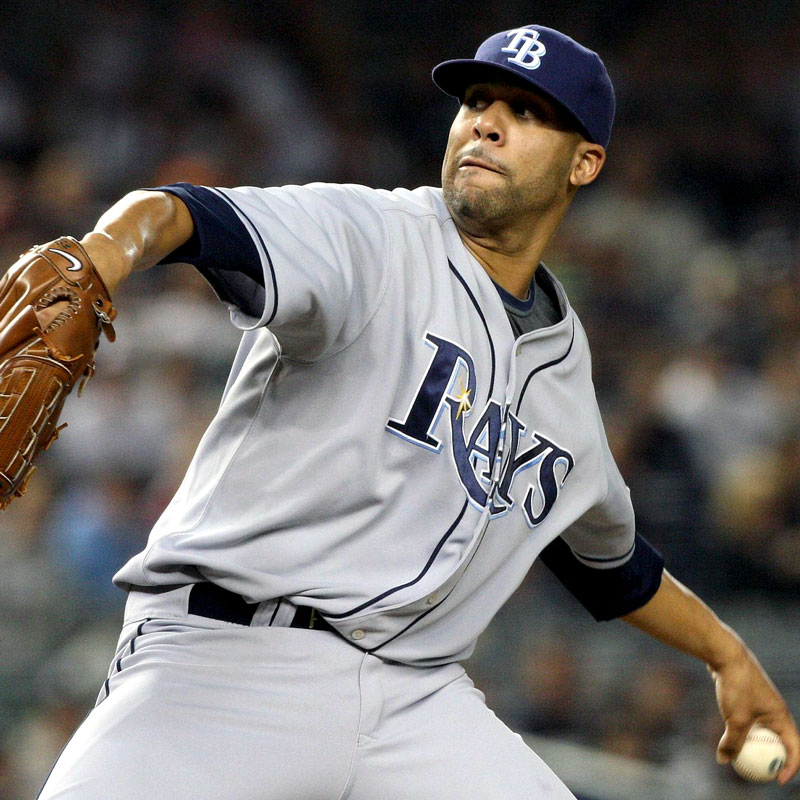 Baseball player in Rays uniform has his arm back, preparing to throw a baseball