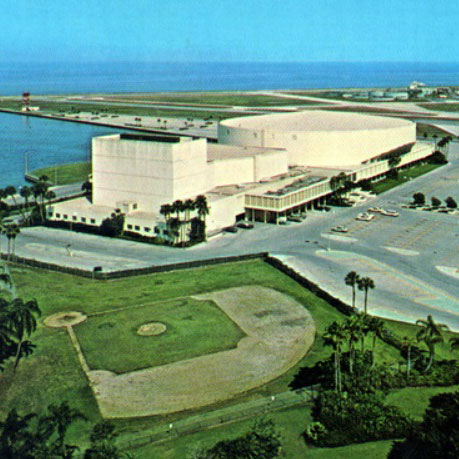 Aerial view of the Bayfront Center in 1988, a large blocky cream-colored building next to the bay