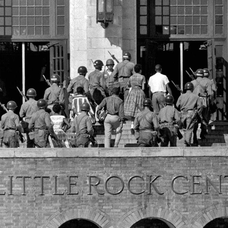 Black-and-white photo of US Army troops escorting teens into Little Rock Central High School