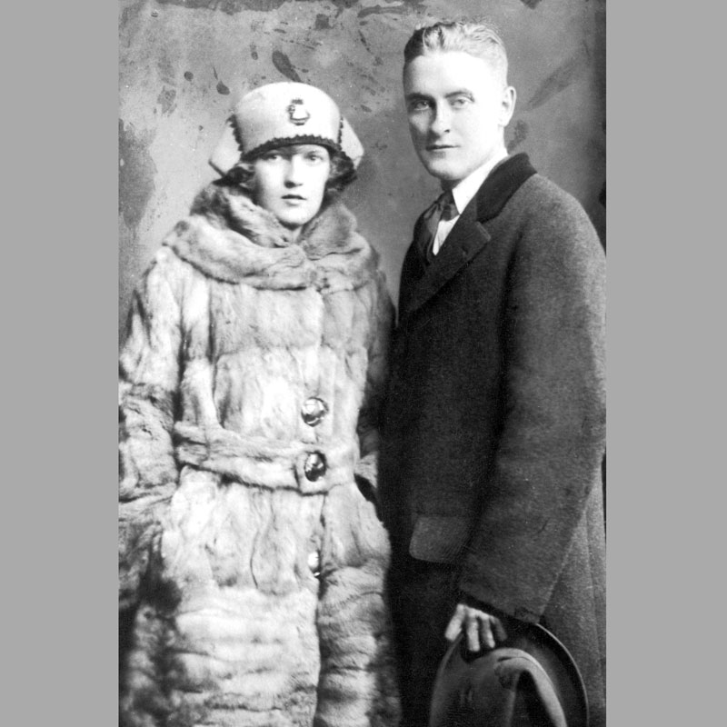 Zelda, wife of F. Scott Fitzgerald, stands next to her husband in a black-and-white photo. The young couple is dressed for winter.