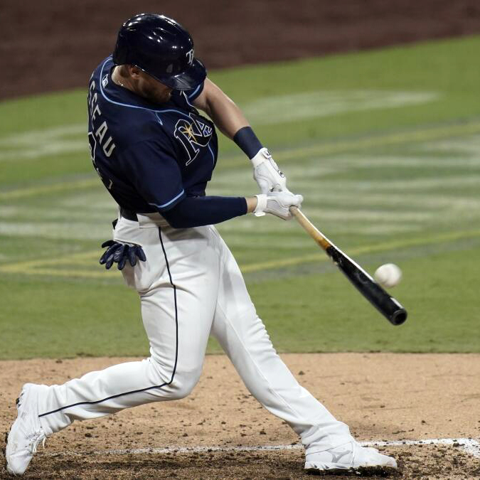Mike Brosseau in Rays' uniform in mid-swing with his bat about to make contact with the pitched baseball