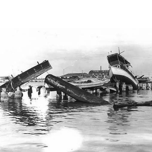 Black and white photo from the damage caused by the 1921 hurricane, including what appears to be a destroyed doc and capsized boat