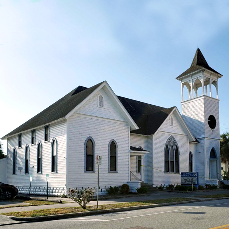 Small white church building with a bell tower on the right and a central entrance door