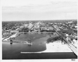 Aerial view of downtown looking west on Central Ave from Tampa Bay. The Central Yacht basin is in the center, with new fill extending the land on the south side of the pier approach, as well as north breakwater. The Spa building, Comfort Station No. 1 (Little St. Mary's), and the Senior Center can be seen on the on south side of the pier approach to the left, and Demens Landing Park can be seen to the right. c. 1950