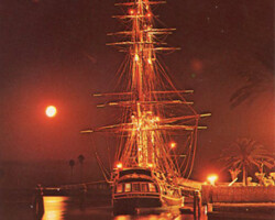 Night view of MGM's Bounty, moored at the pier in St. Petersburg Florida.(3 Copies) Tall ship docked at a harbor at night, illuminated with warm lights reflecting on the water beneath a full moon
