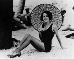Woman poses in a bathing suit with parasol, while on the beach, possibly in Gulfport. c. 1930. Woman poses in a bathing suit with parasol, while on the beach, possibly in Gulfport. c. 1930.