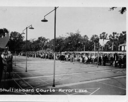 Historic black-and-white photo of the Shuffleboard Courts at Mirror Lake, with players and spectators along multiple courts lined by lamp posts and trees