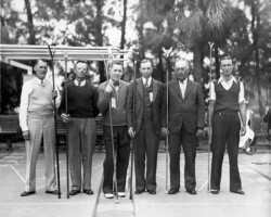 Six men posing outdoors with shuffleboard cues, likely at a tournament, in a vintage black-and-white photograph