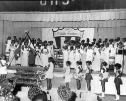 Students in formal attire and cheerleaders on stage at a school event beneath a Gladiator Grandeur banner